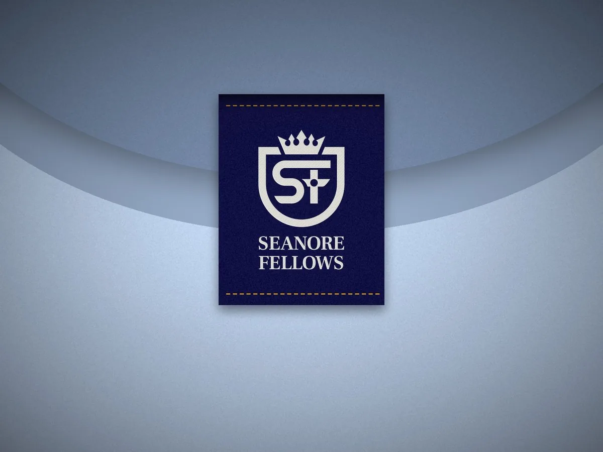 Navy woven neck label with the white signature crest inside a light blue shirt collar